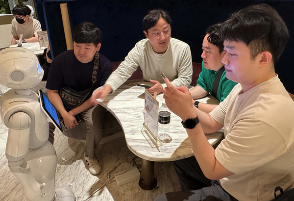 프로그램에 참여한 LG유플러스 직원들이 일본 도쿄의 PEPPER PARLOR 카페에서 서비스 로봇 이용을 체험하고 있다. (사진=LG유플러스 제공)